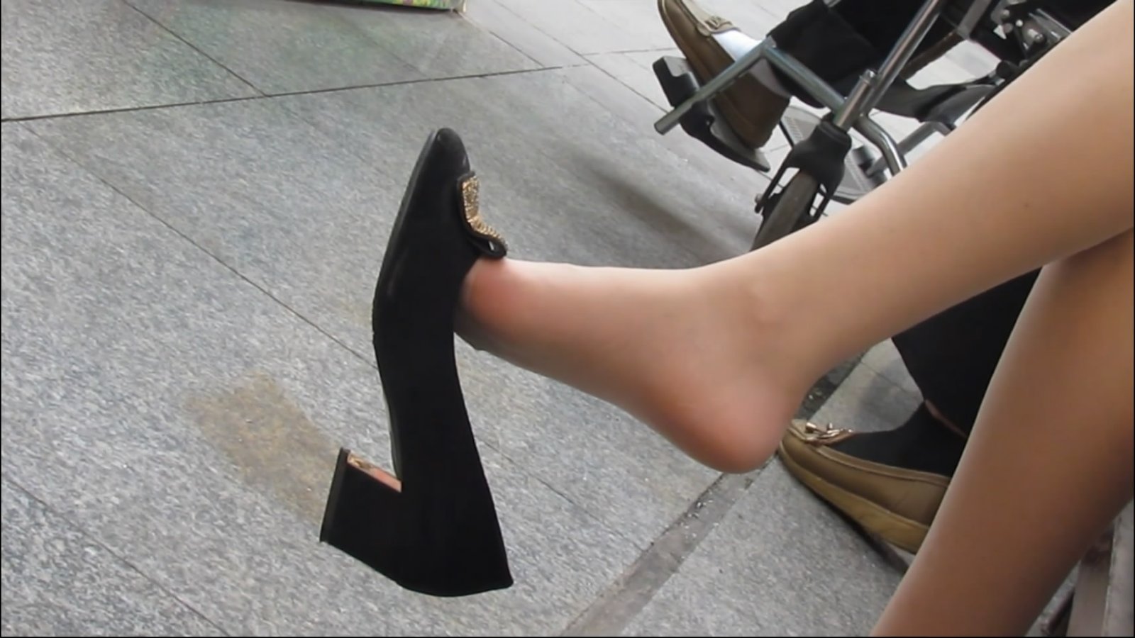 Brochure with feet dangling above black high heels